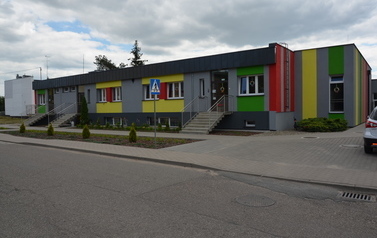 Przedszkole Bajka w Lubaszu, jednopiętrowy budynek, szara elewacja z pionowymi pasami w kolorach ż&oacute;łtym, czerwonym, zielonym. 