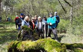Grupa ludzi pozująca do pamiątkowego zdjęcia. Stoją w lesie, ubrani na sportowo z kijkami do nordic walking w dłoniach. 